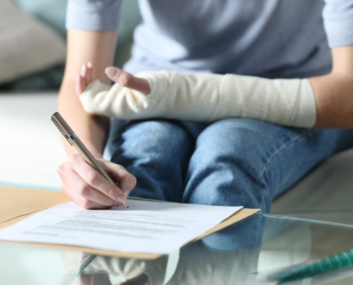 Front view of someone with an arm cast signing a document
