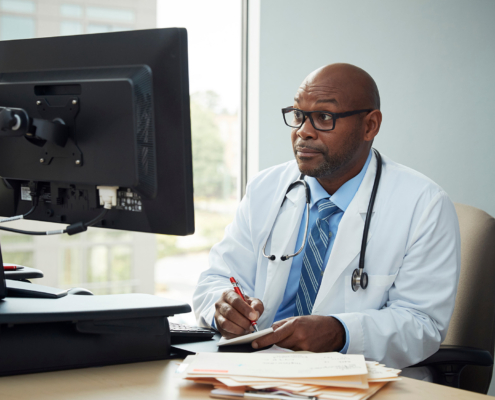 Doctor writing information from a computer