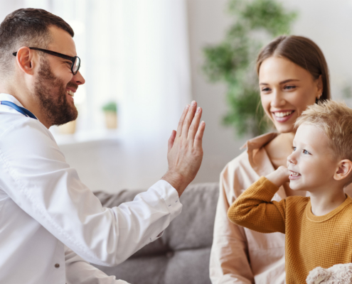 family doctor pediatrician conducts examination of child boy and giving high five to him