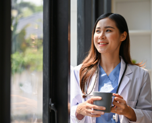 doctor sipping coffee by the window in her hospital office